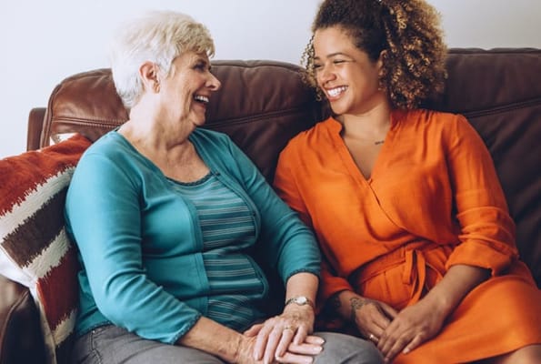 Two smiling women talking on a couch in a common area