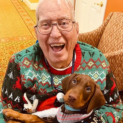 Resident smiling with a dog in a cozy living area