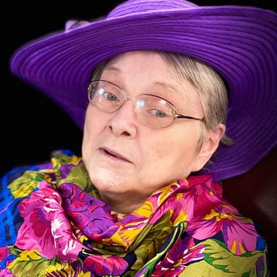 A resident wearing a purple hat and colorful scarf