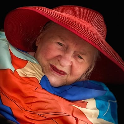 An elderly woman wearing a colorful scarf and red hat