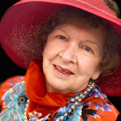 Resident smiling in a colorful outfit and hat