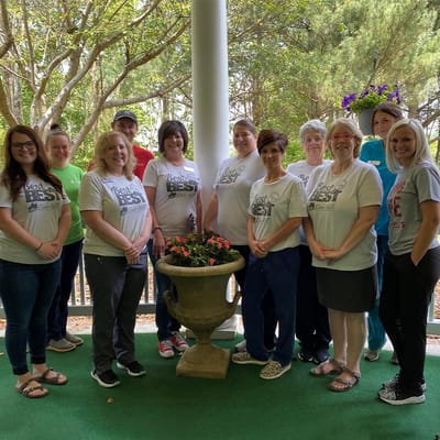Staff members posing together outdoors near a flower pot