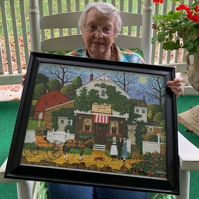 Resident proudly displaying her artwork indoors