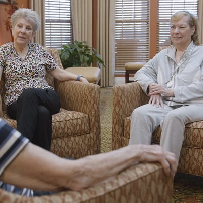 Two residents engaged in conversation in comfortable chairs