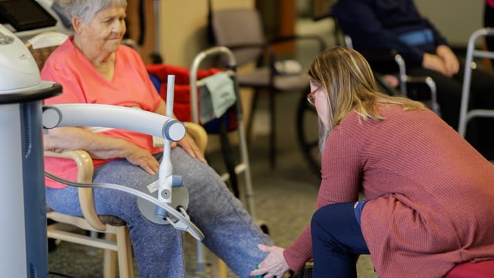 Staff assisting an elderly resident in an interior setting