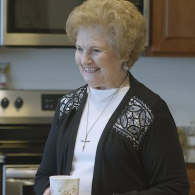 A smiling resident holding a cup in a kitchen