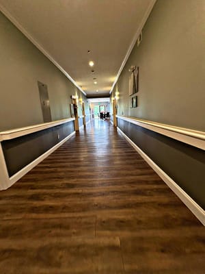 A long hallway with wooden floors and ambient lighting