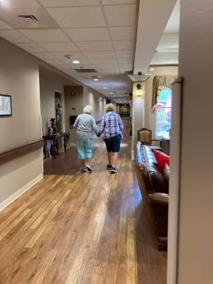 Two residents walking hand-in-hand down a corridor