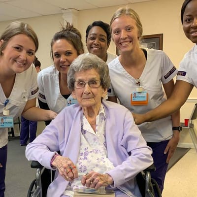 Residents and staff smiling together in an activity room