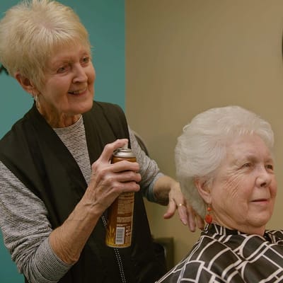 Resident receiving a hair styling in a salon setting
