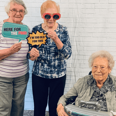 Three residents posing with fun signs at an event