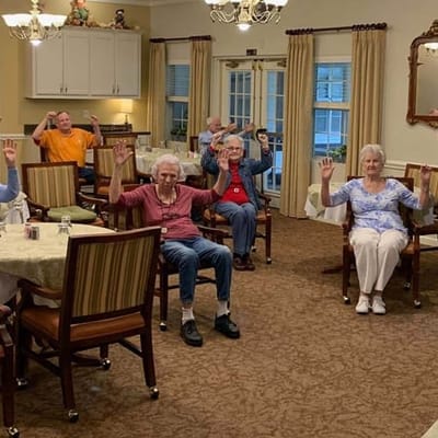 Seniors participating in a seated exercise class in a common area