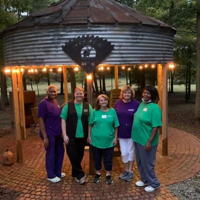 Staff members posing outside a covered area in a garden