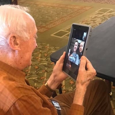 Senior resident video calling family on a tablet