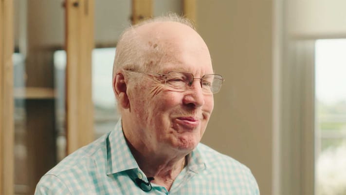 A smiling elderly man in a cozy interior setting