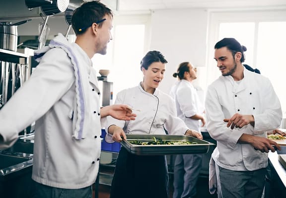 Chefs preparing dishes in a kitchen environment