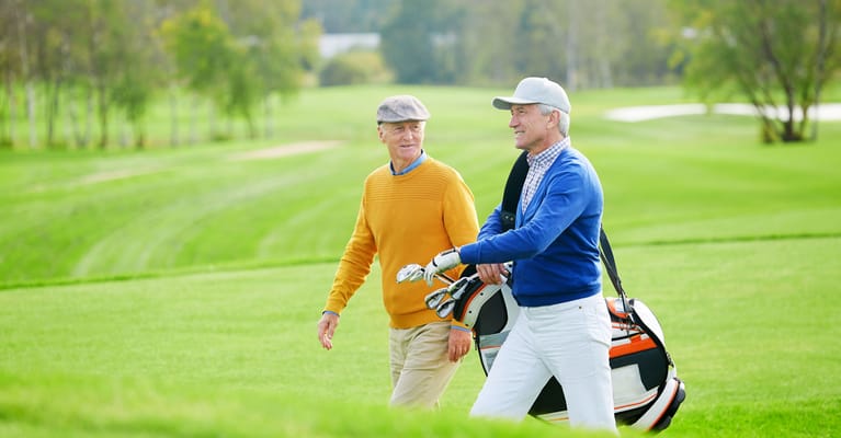 Two seniors walking on a golf course