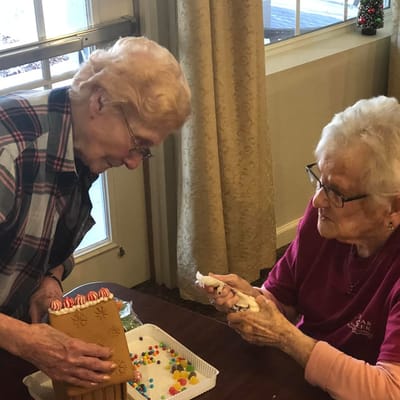 Residents decorating gingerbread houses in an activity room