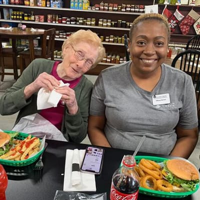 Resident and staff enjoying meals together at a dining table