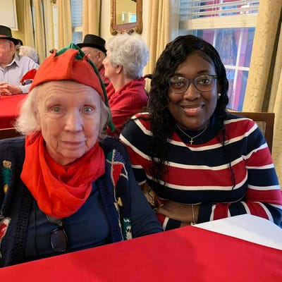 Resident and staff member posing together at a dining area