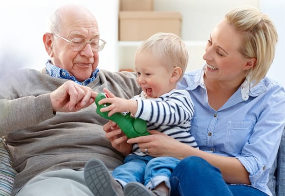 A senior man playing with a child and a woman