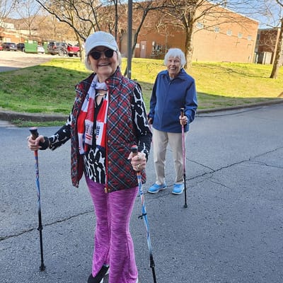 Two residents walking outdoors with walking poles