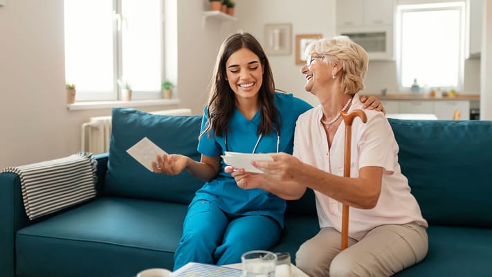 Nurse and resident laughing together in a cozy living room