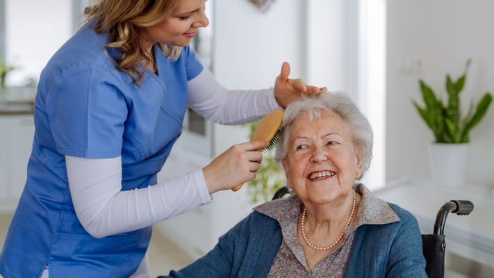 A caregiver styling a resident's hair in a bright interior