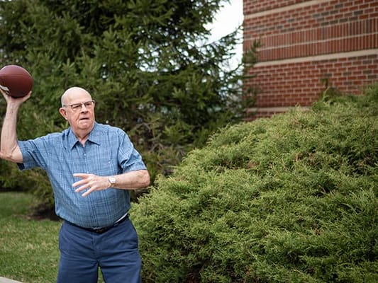 A senior man throwing a football outdoors