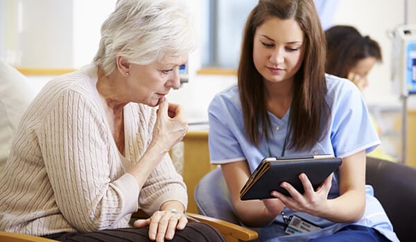 Nurse assisting a senior resident with a tablet