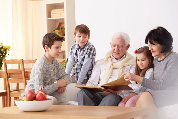 Elder man reading a book with children