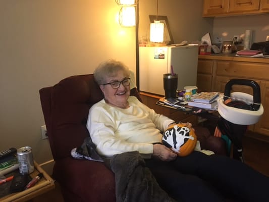 Resident in a cozy chair holding a decorated pumpkin