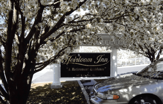 Facility sign for Heirloom Inn under flowering trees