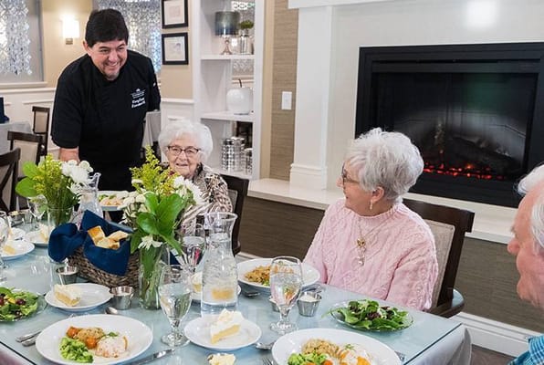 Residents enjoying a meal with a staff member