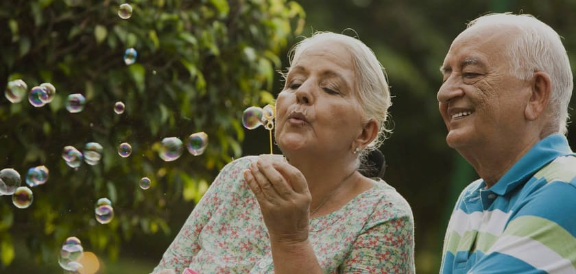 A senior couple blowing bubbles in a garden