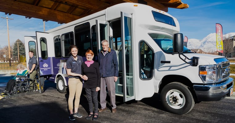 Residents and staff by a facility transport van