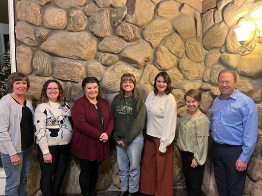 Staff members gathered in a common area with a stone wall