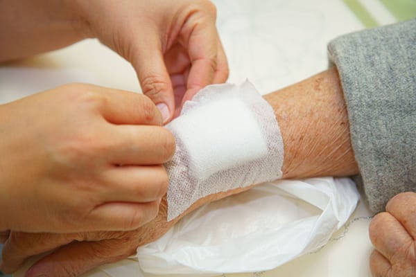 Nurse applying a bandage to an elderly person's wrist