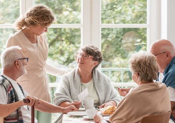 Residents enjoying a meal with staff in a cozy dining setting
