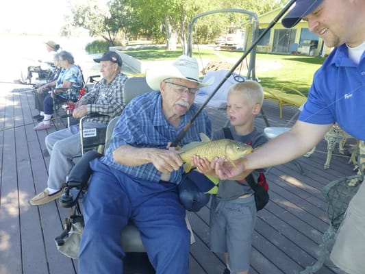 Elderly man fishing with a young boy outdoors
