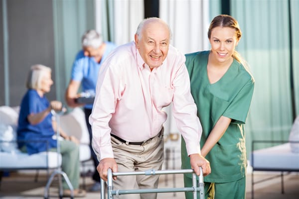 Staff assisting a resident with a walker outdoors