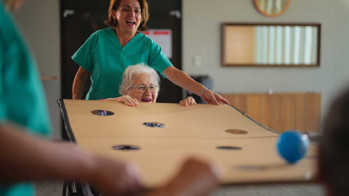Staff assisting a resident in a lively activity