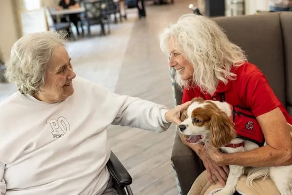Resident interacting with staff and a therapy dog