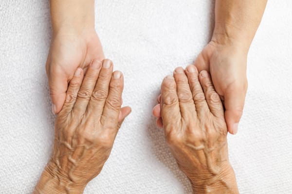 Two pairs of hands holding each other gently