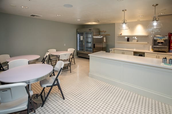 Interior view of a dining room with tables and kitchen area