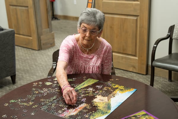 A resident working on a jigsaw puzzle in the facility