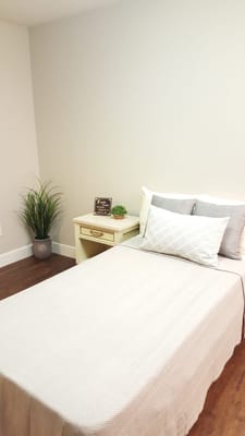 A simple, well-decorated private resident room with a bed and plant.