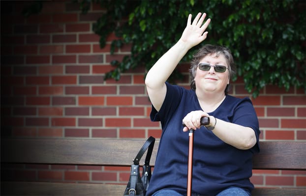 Resident waving while sitting on a bench