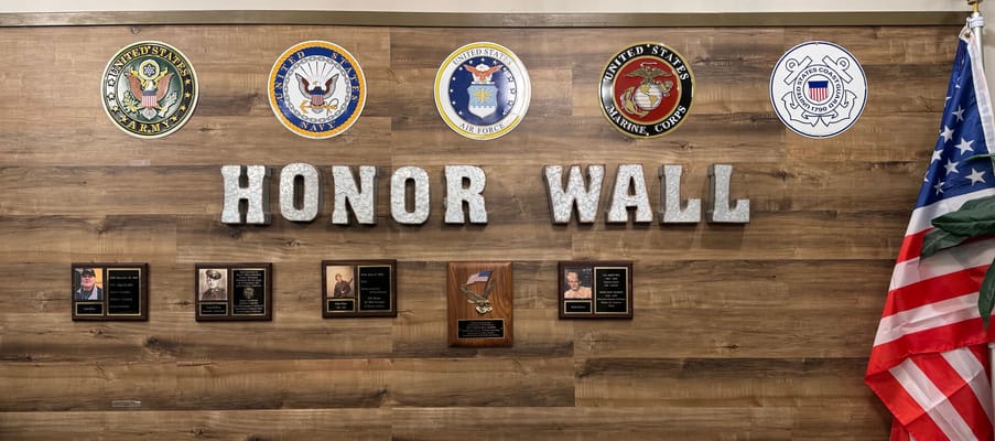 Honor wall displaying military service plaques and emblems
