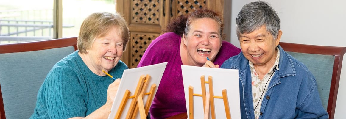 Residents enjoying a painting activity with staff.